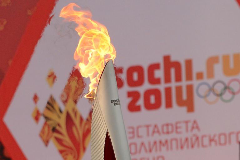 One of the Olympic torches rises in front of a poster with the Sochi 2014 Winter Olympic logo just outside the Red Square in Moscow, on October 7, 2013